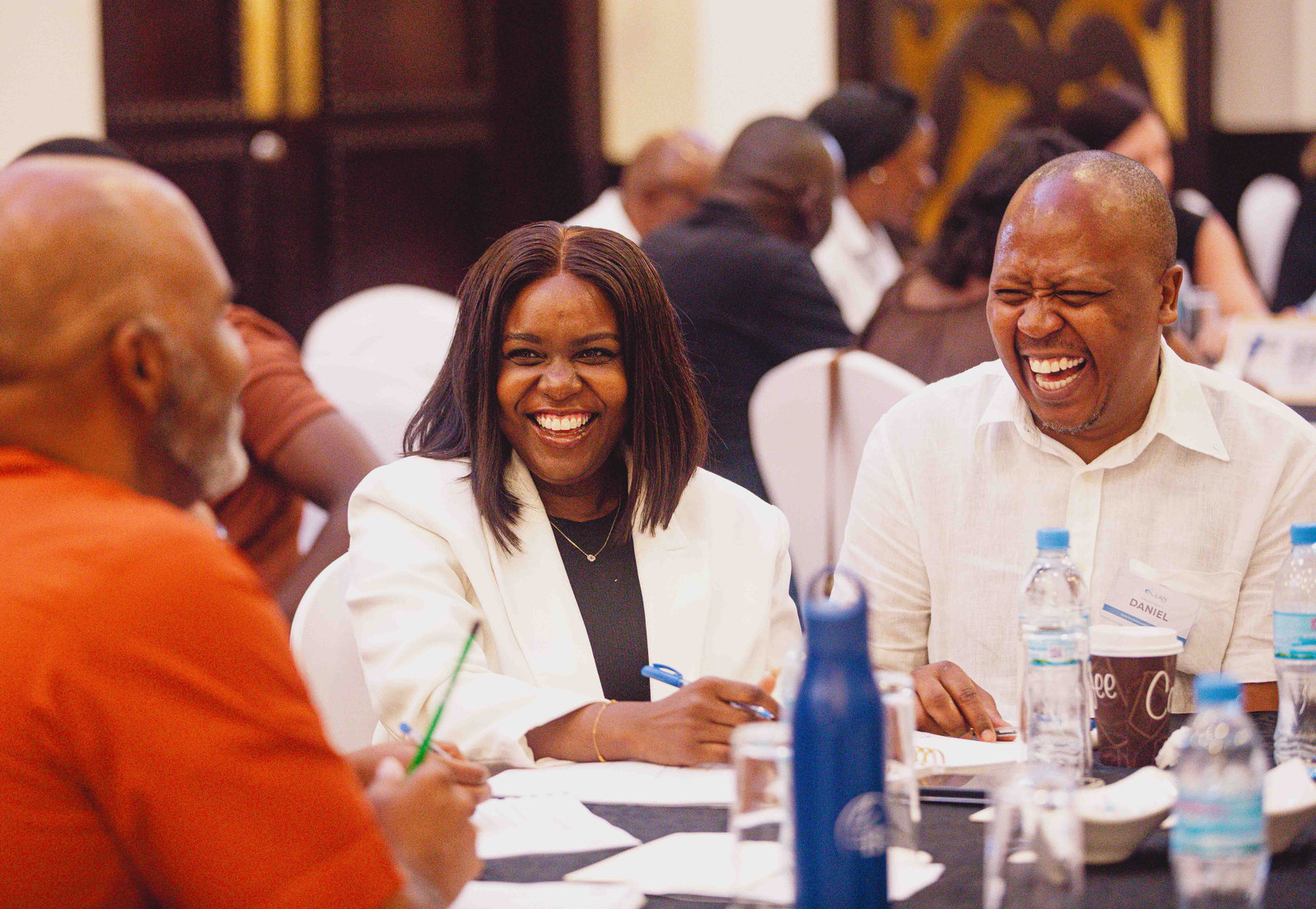 People laugh together around tables at a church gathering