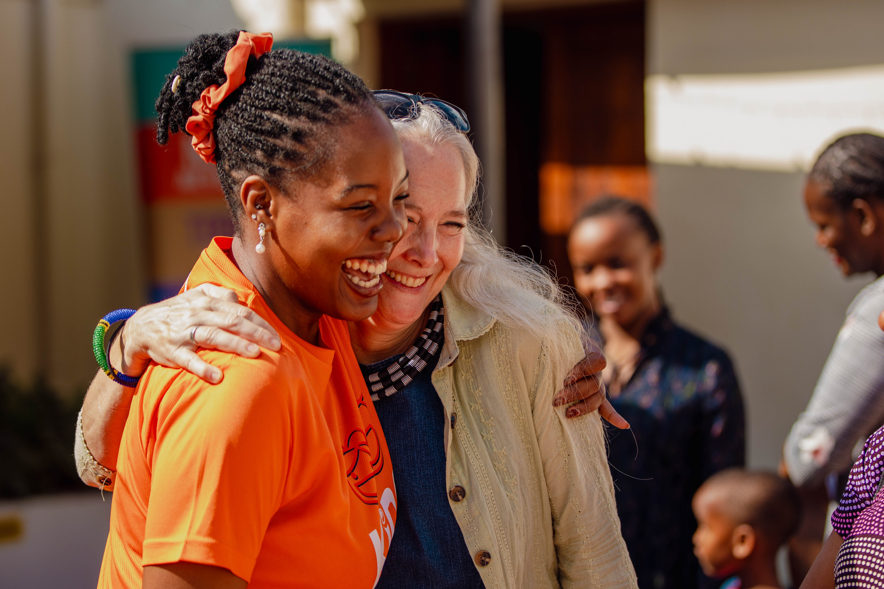 Two women hug and laugh outside