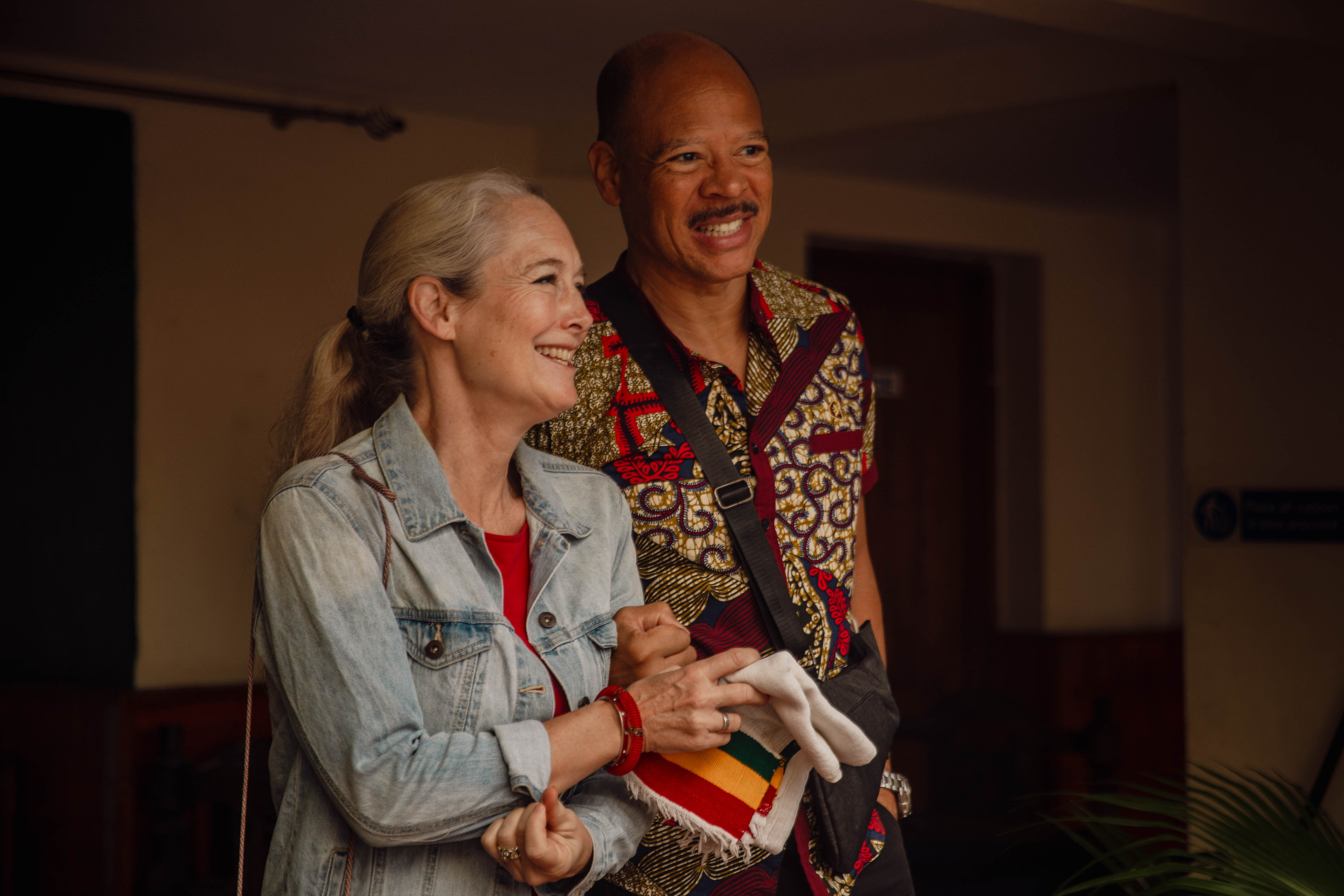 An older man and a woman laugh together, arms linked