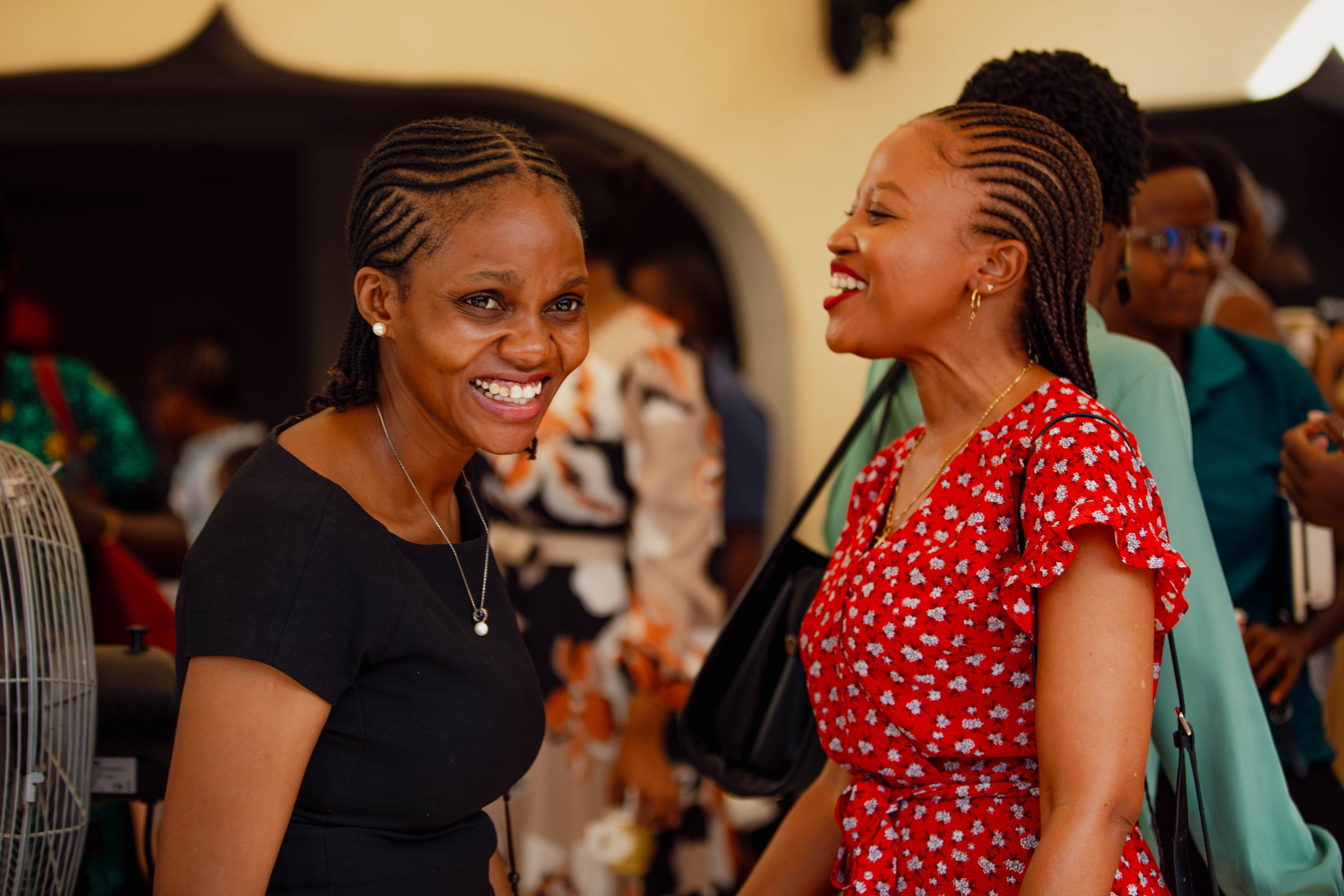 Two women laugh together in the courtyard after the service