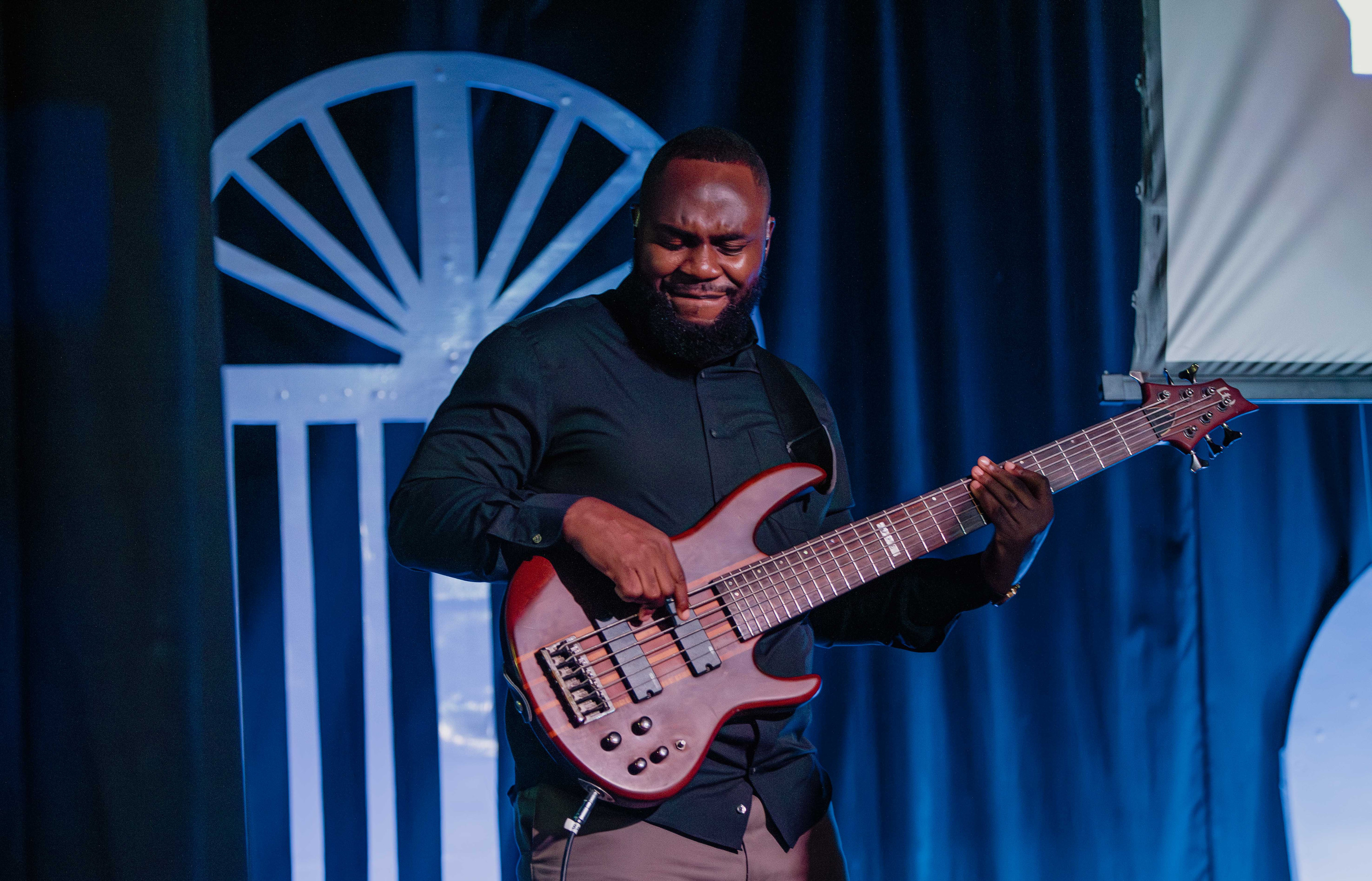 A bass player smiles as he plays under blue stage light