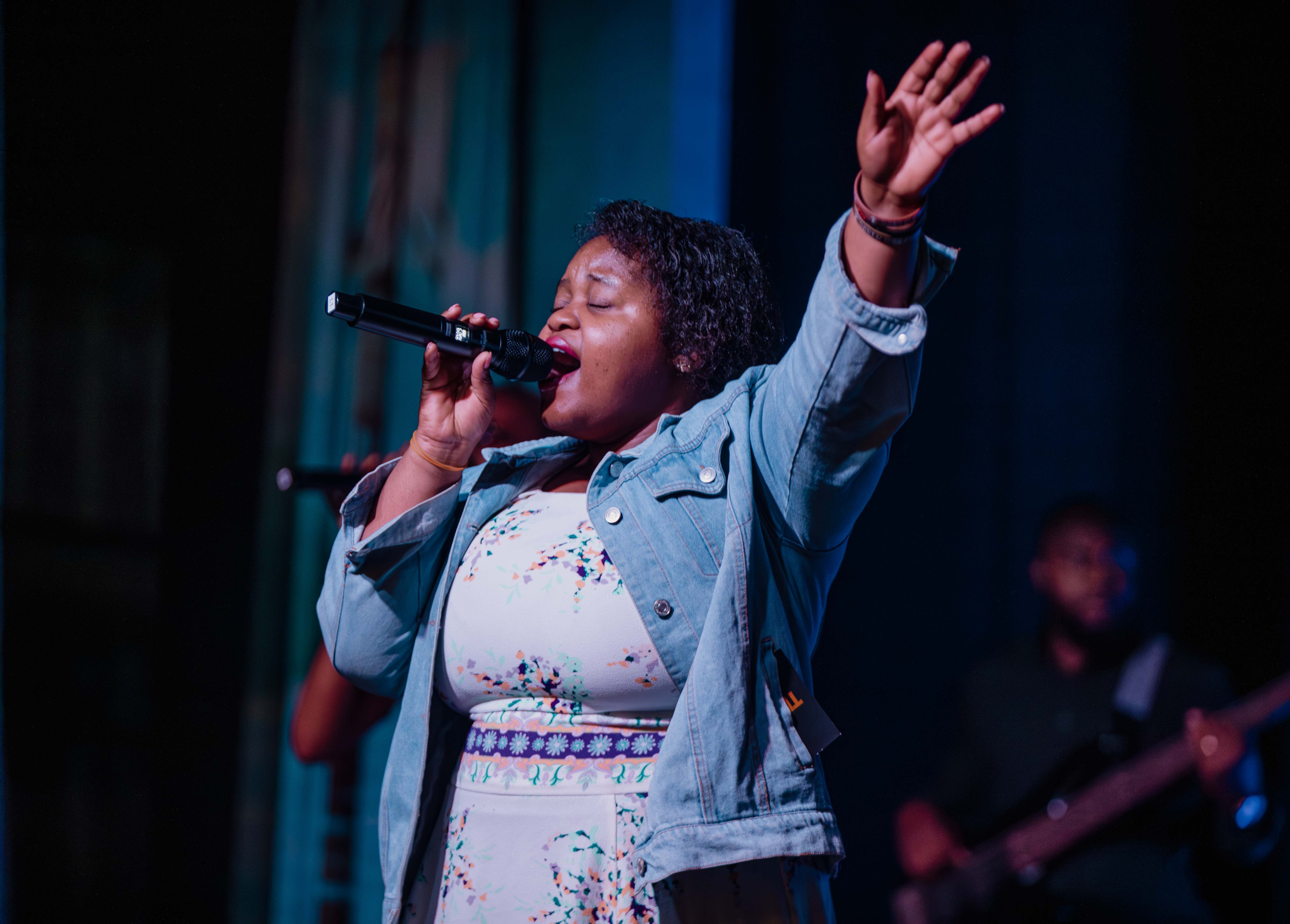 A singer leads worship with her arm raised