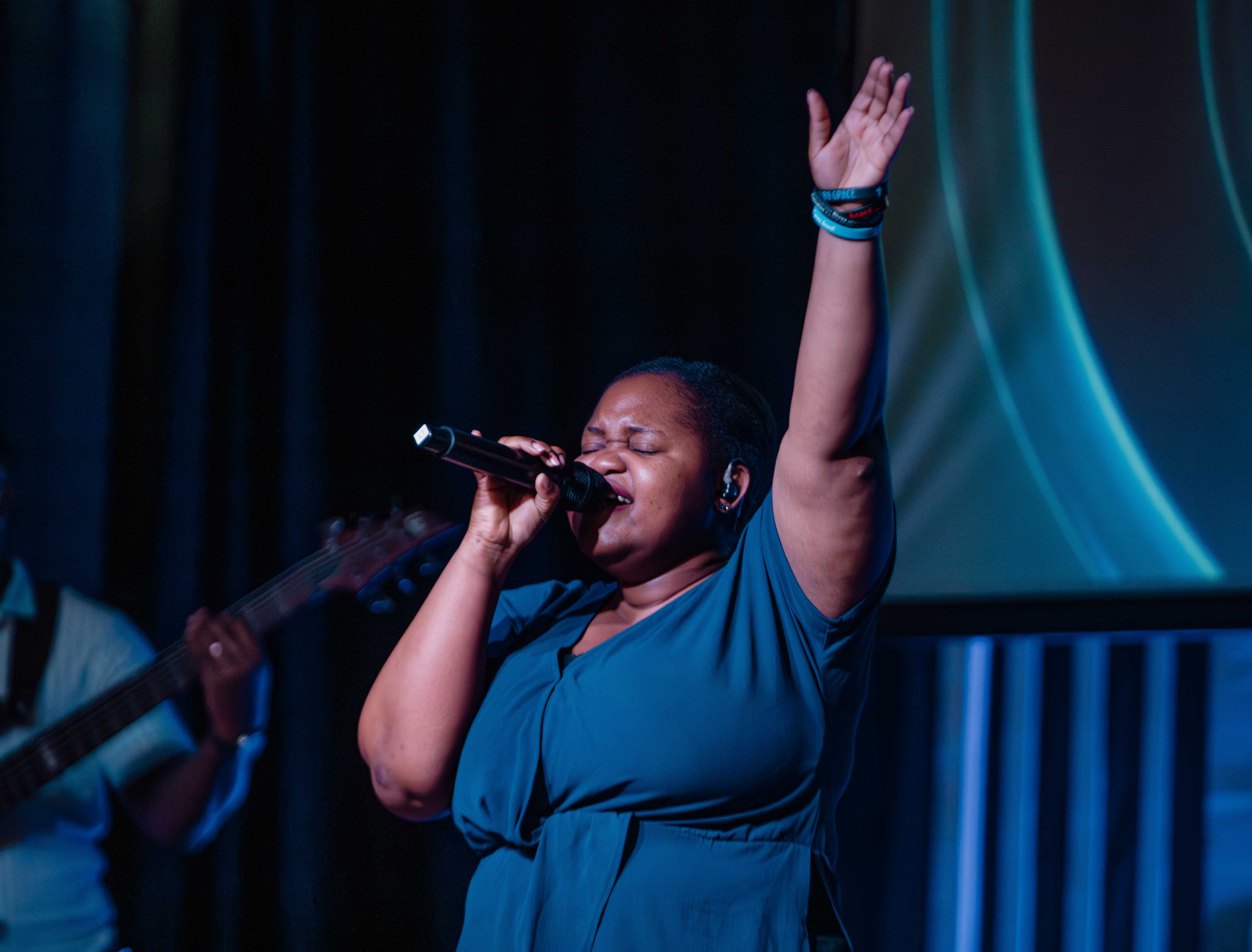 A singer leads worship with her arm raised