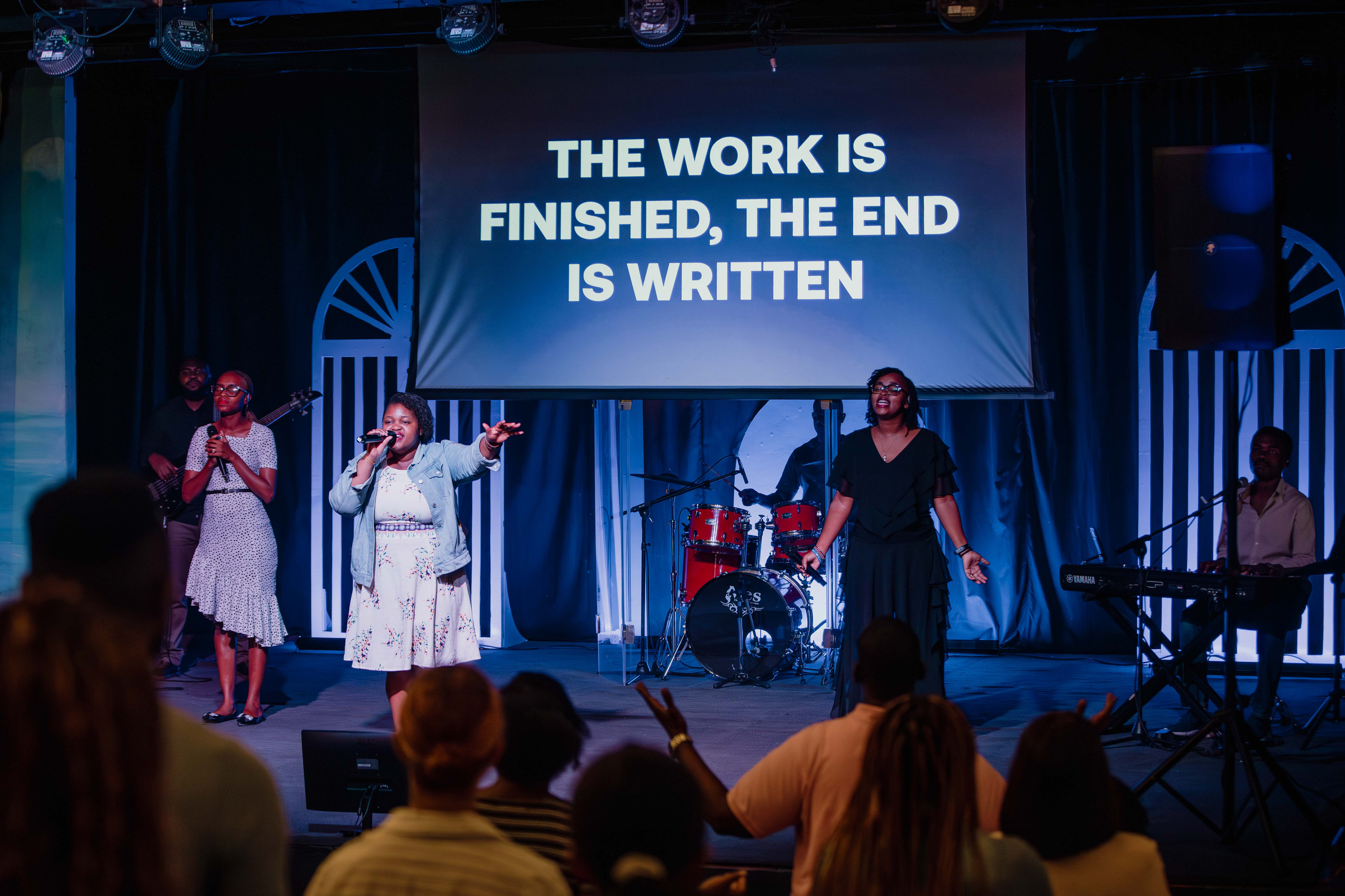 The band and singers lead worship on stage under blue light