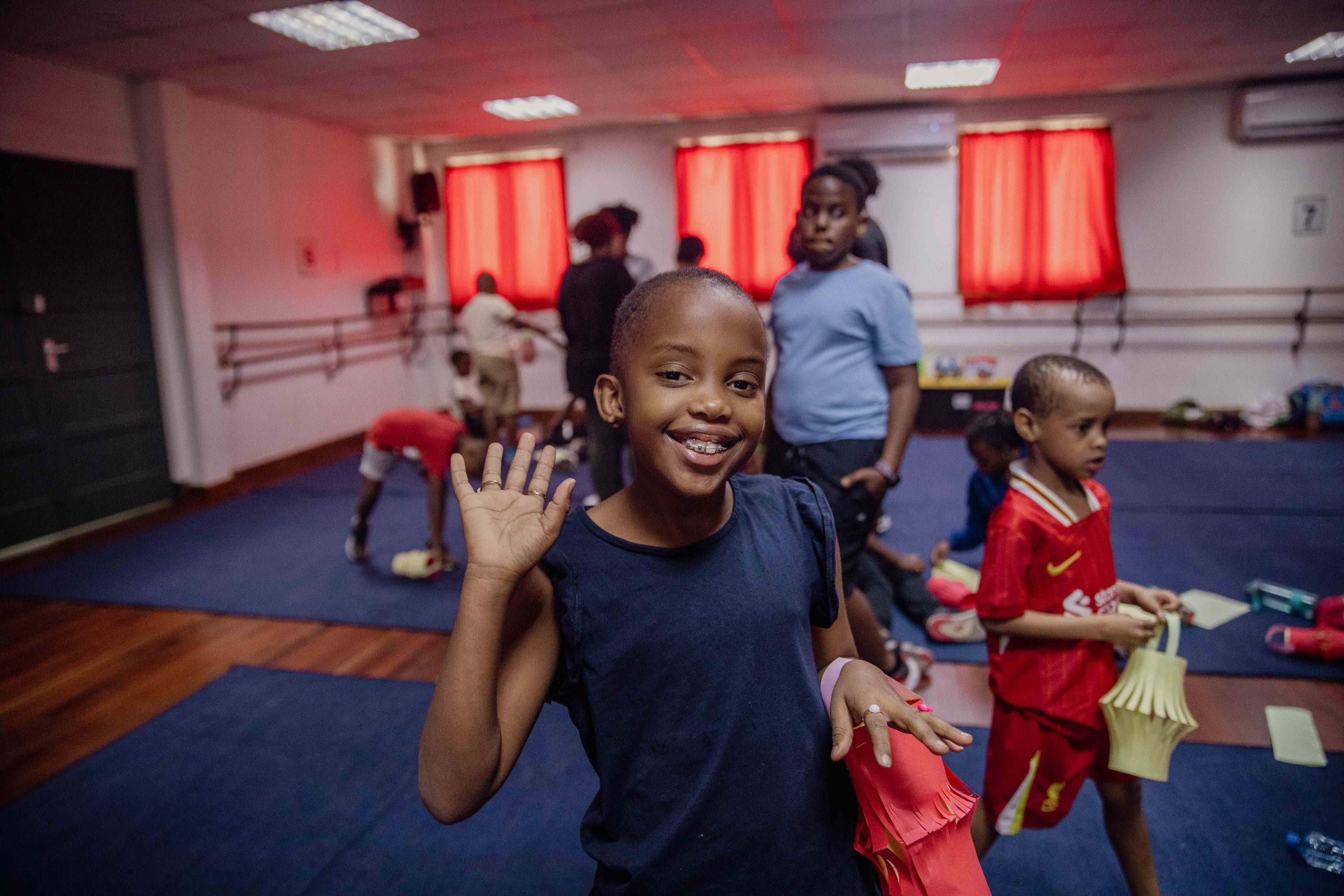 A girl waves and smiles at summer camp