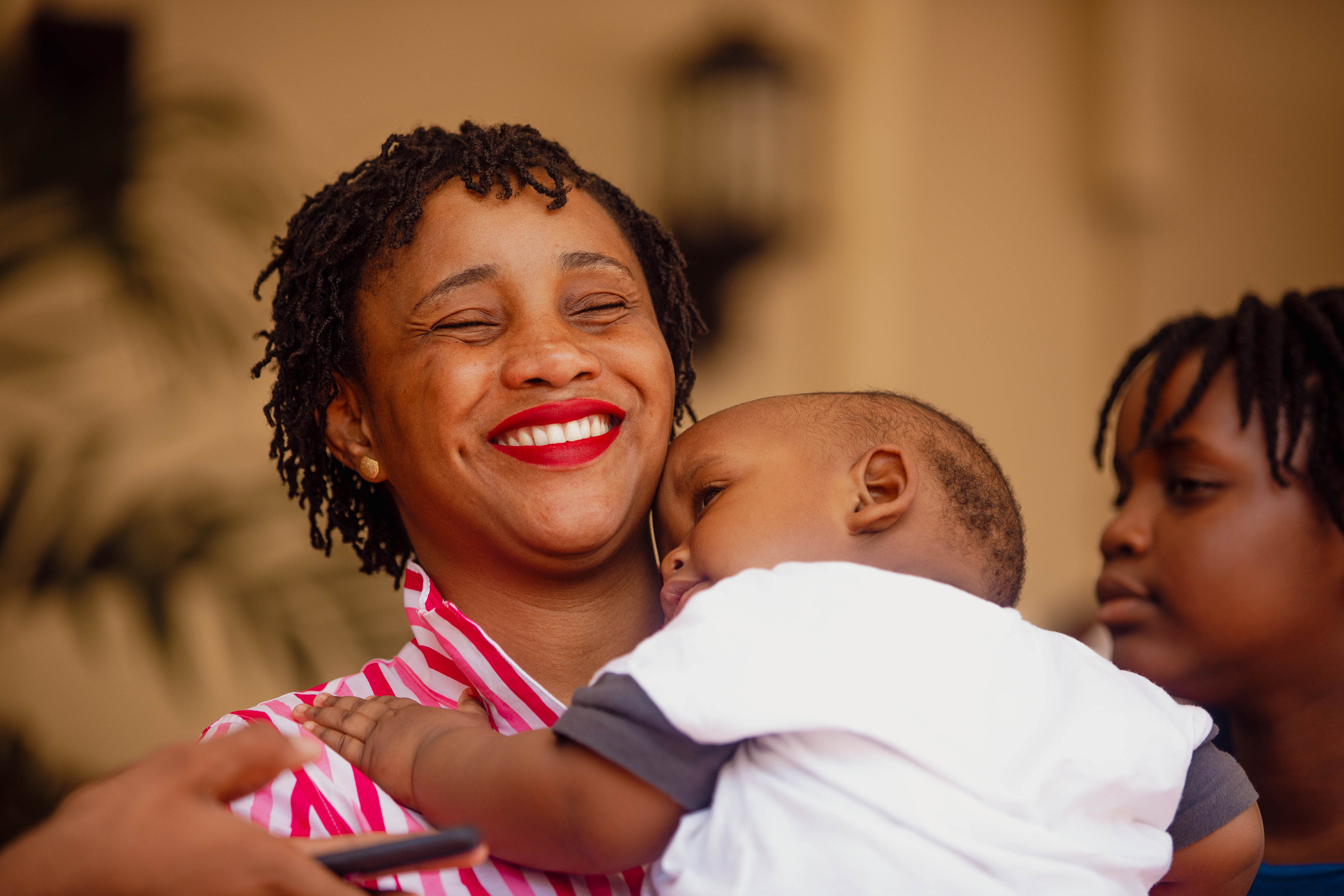 A woman laughs as she holds a small child close