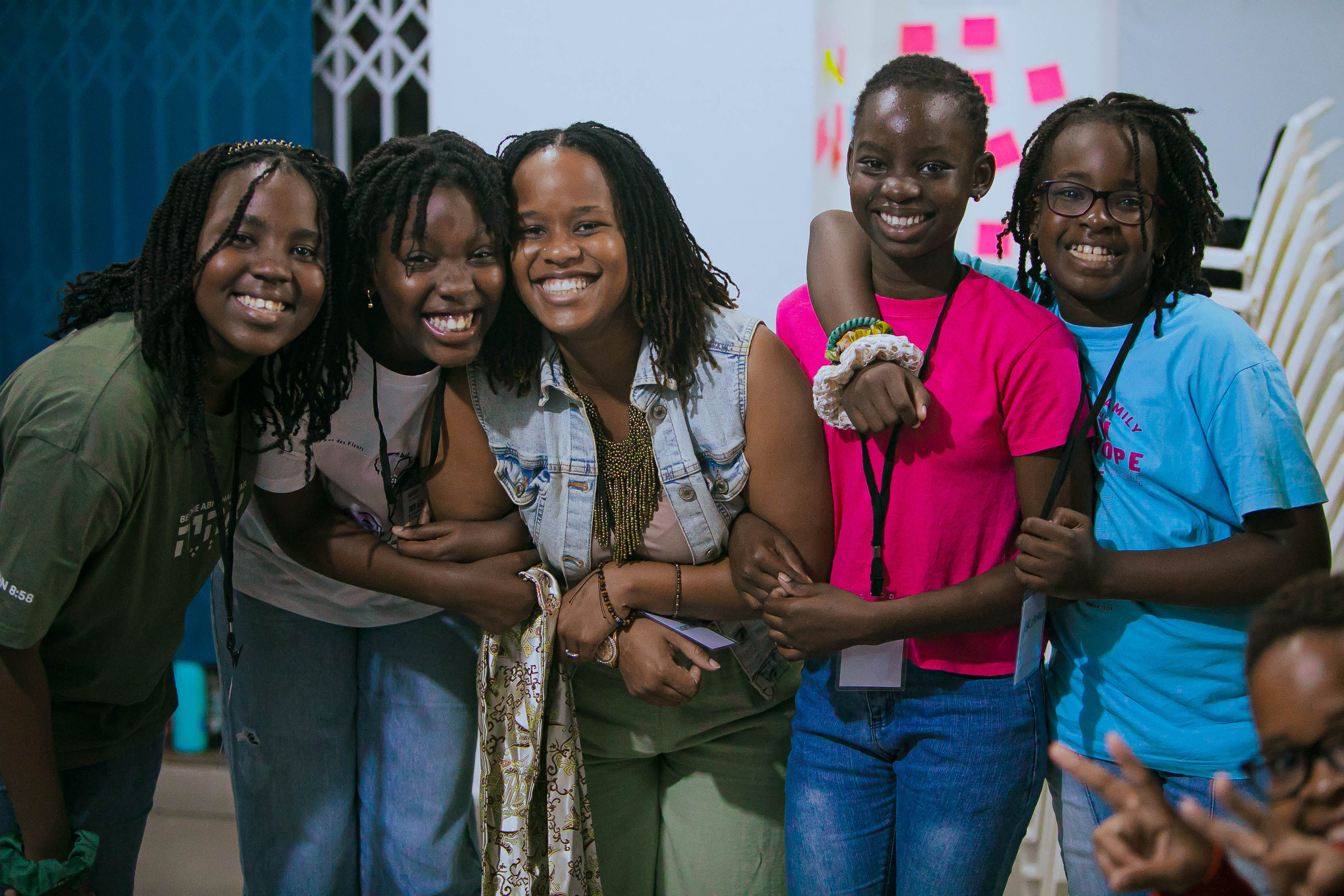 A group of teenage girls laugh together, arms linked