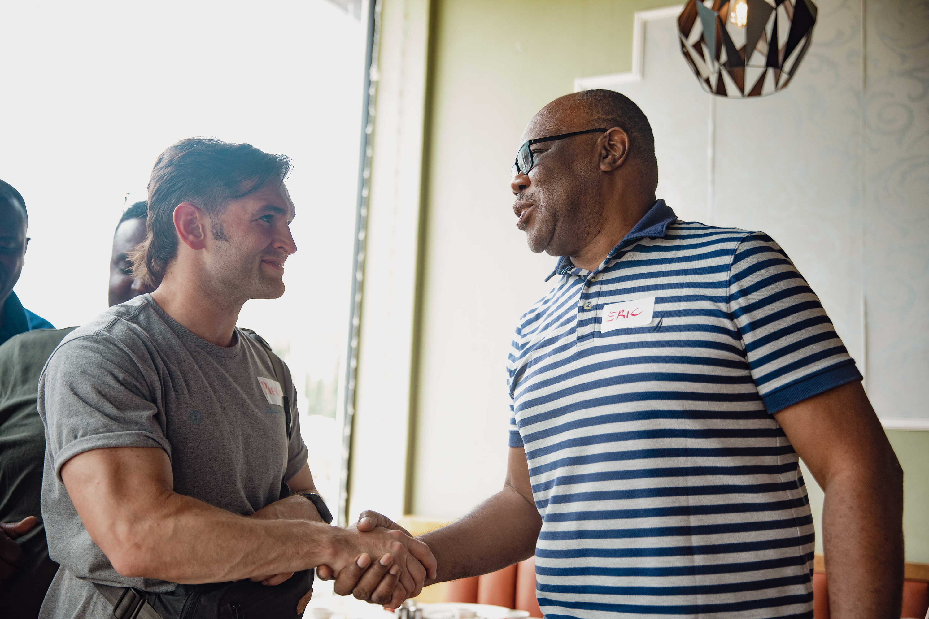 Two men shake hands and smile at the men's breakfast