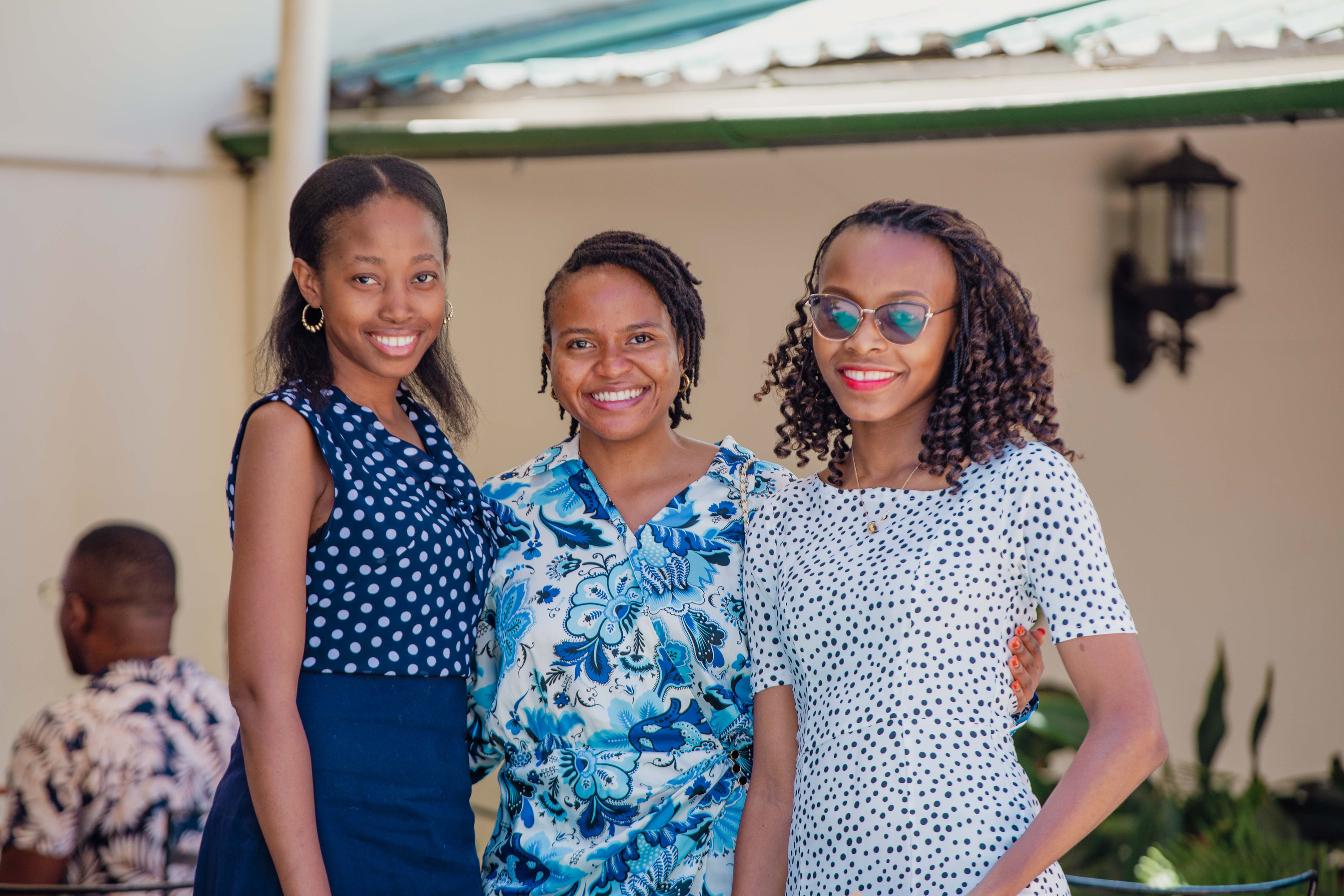 Three women smile together outdoors