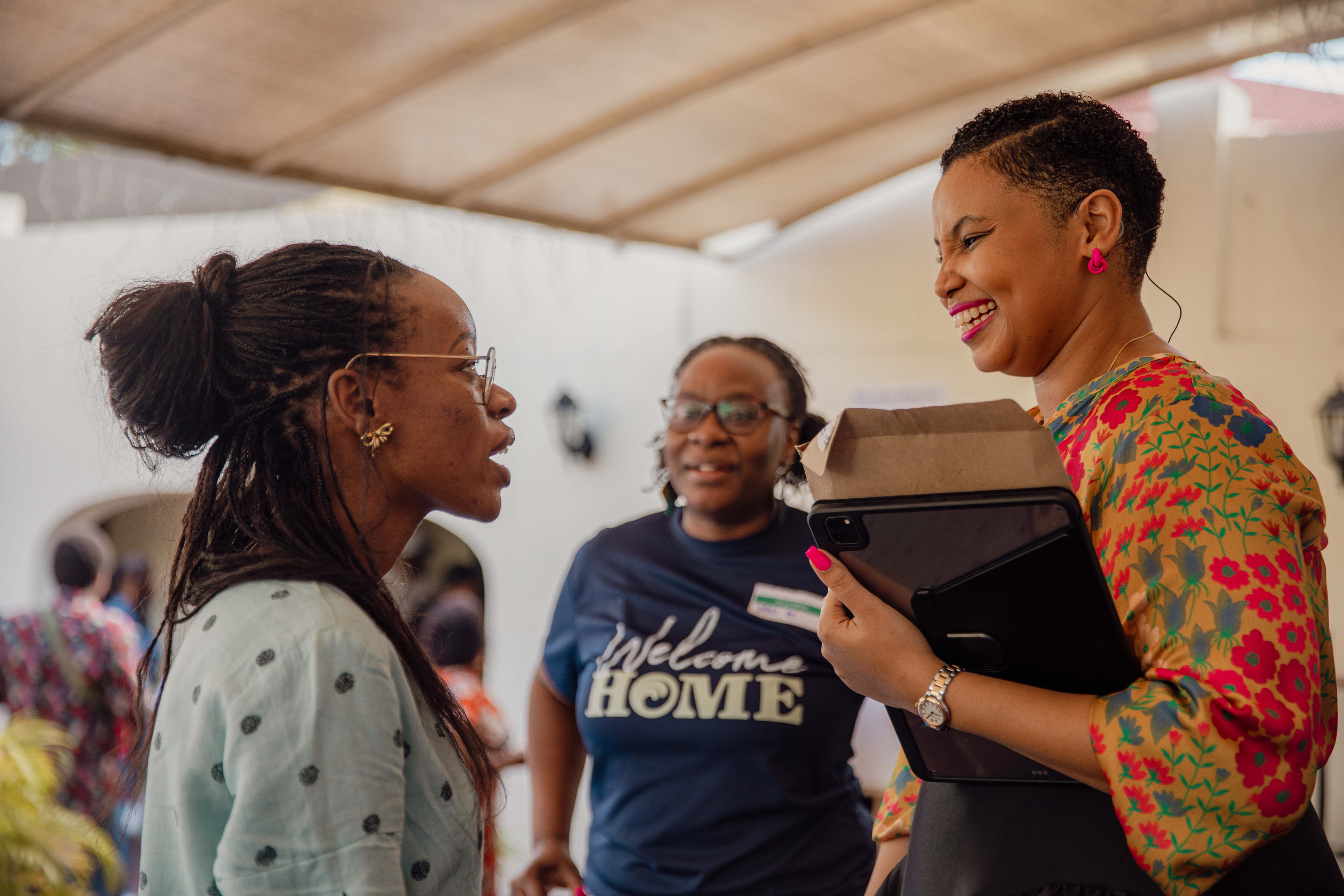 A volunteer in a Welcome Home T-shirt chats with two women in the courtyard