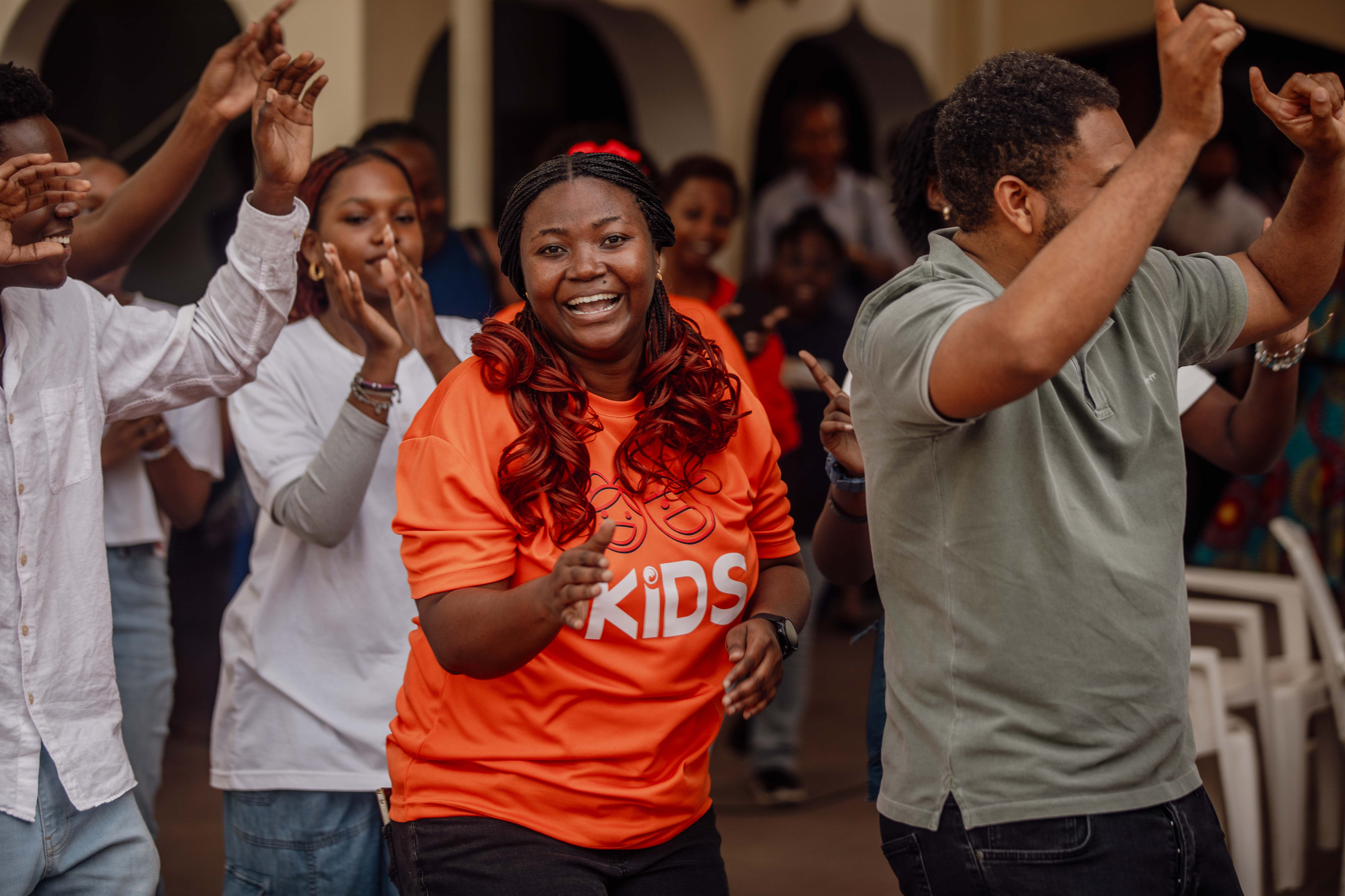 A woman in a KIDS T-shirt and a man dance in worship