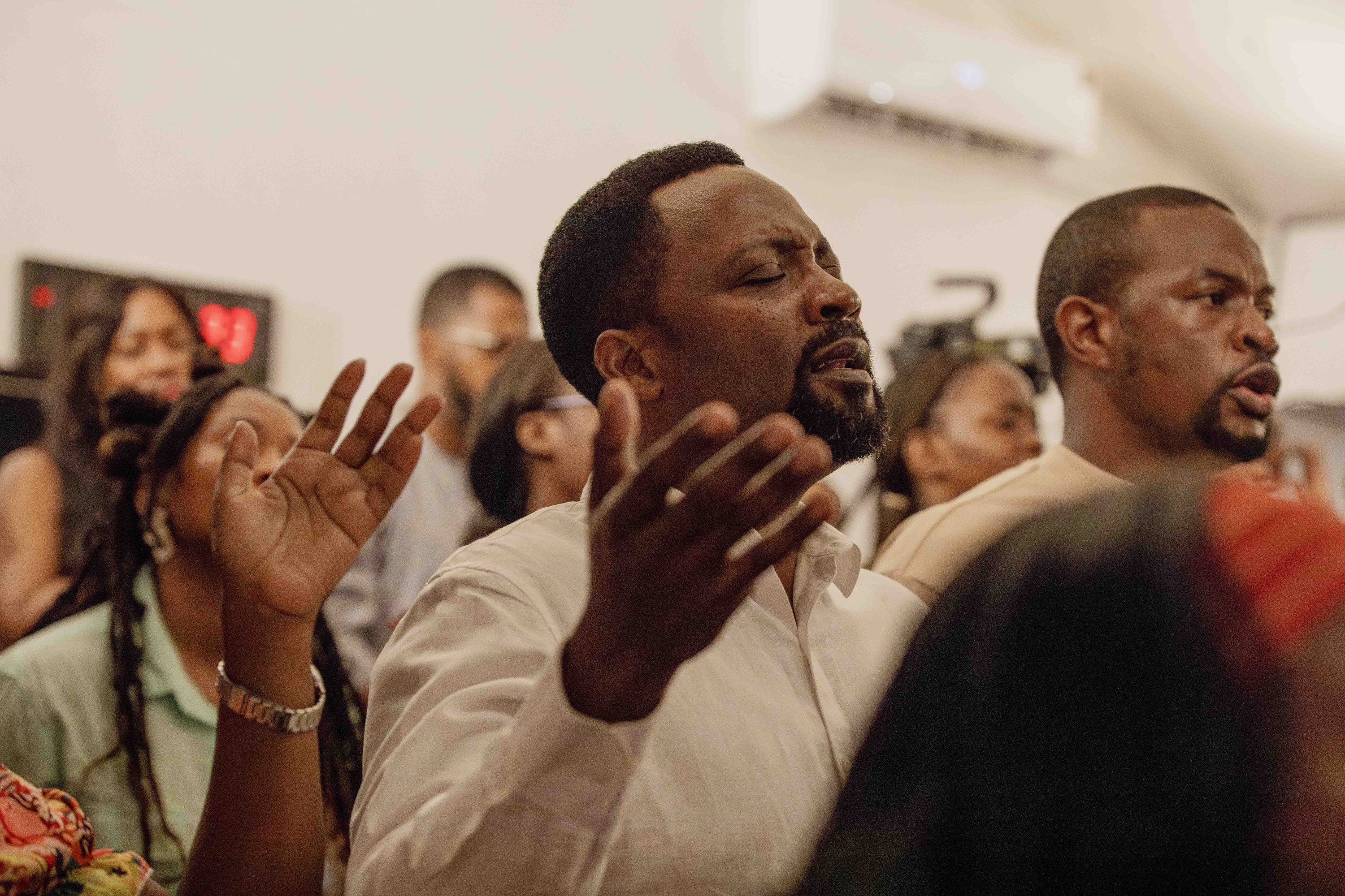 Two men worship with eyes closed and hands open